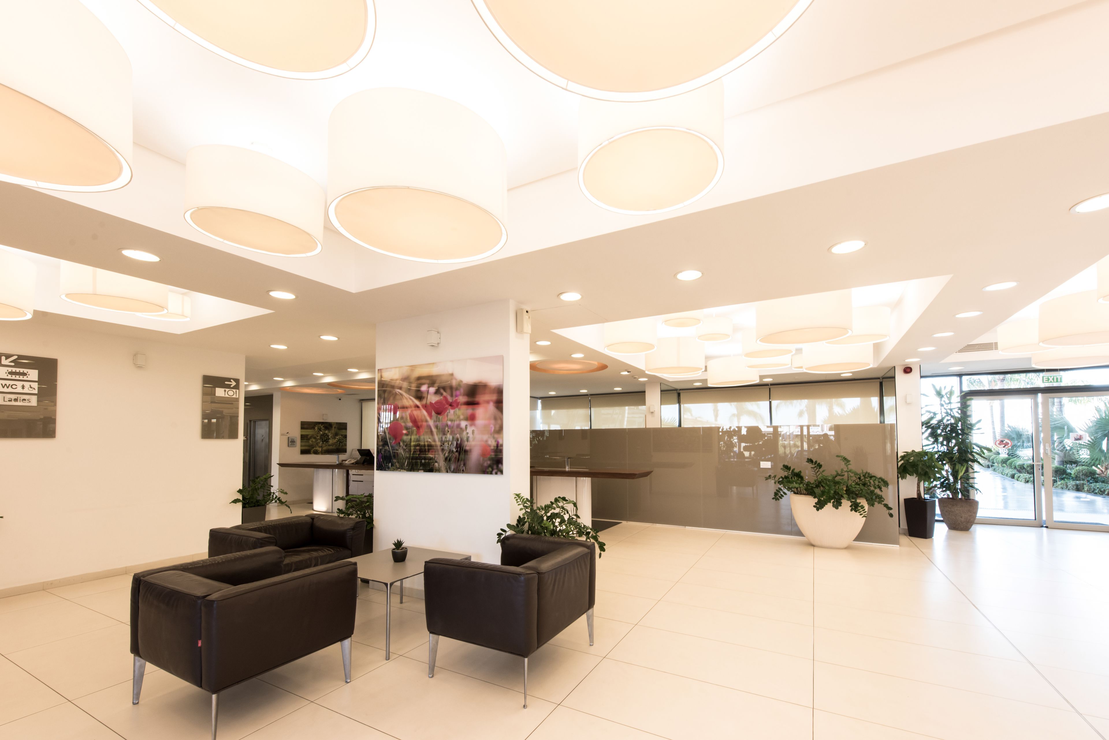 A modern lobby with a reception desk, seating area, and large windows.