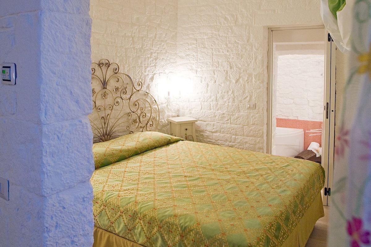 Une chambre à coucher avec un lit, une table de chevet et une fenêtre.