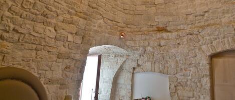 A room with a stone ceiling, a bed, a nightstand, a dresser, and a chandelier.