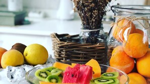 A fruit platter with various fruits and a glass jar of oranges on a kitchen counter. - Le Alcove Luxury Resort nei Trulli (Alberobello)