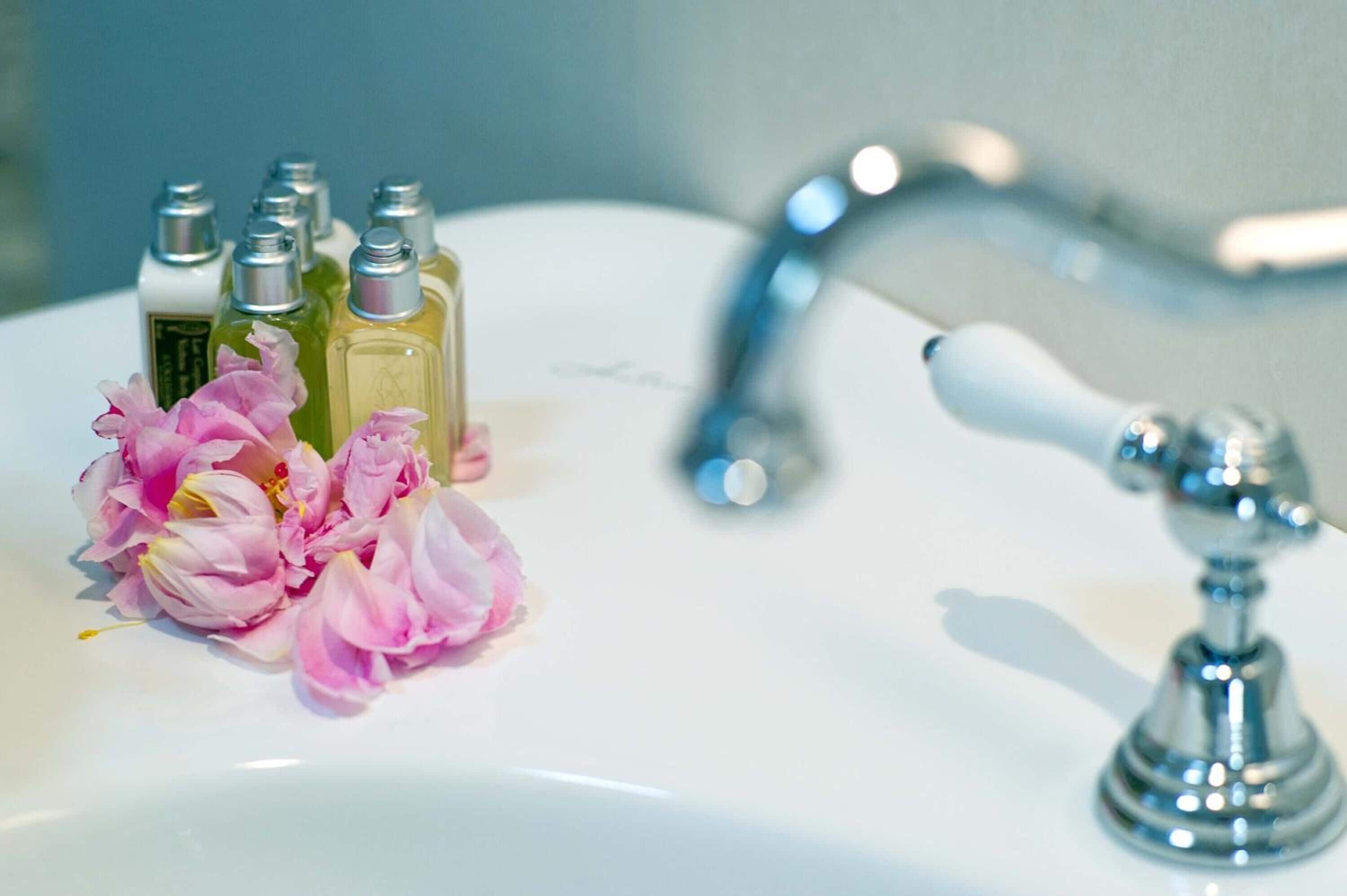 Un lavandino da bagno con un rubinetto e diverse bottiglie di sapone liquido.