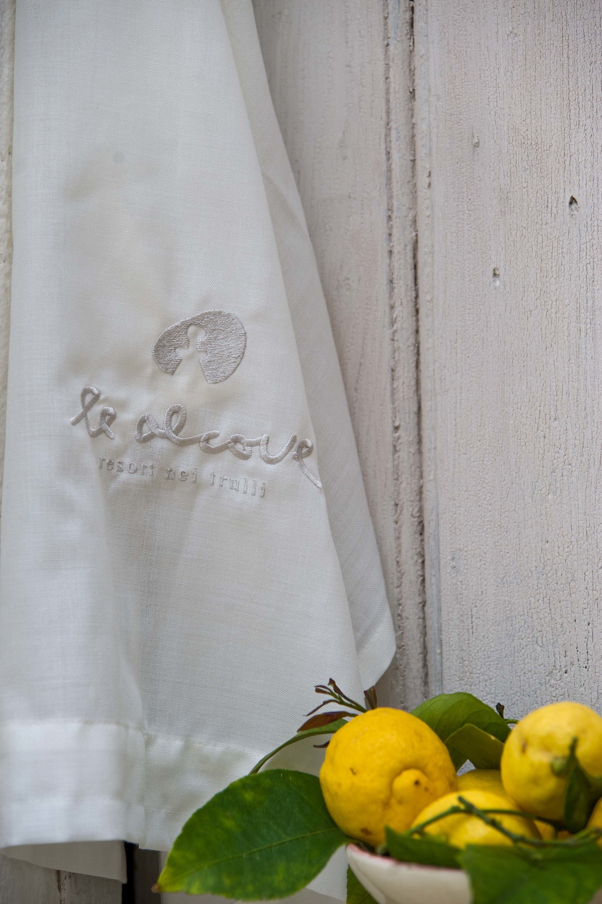 Cortina blanca con texto bordado y un cuenco de limones.