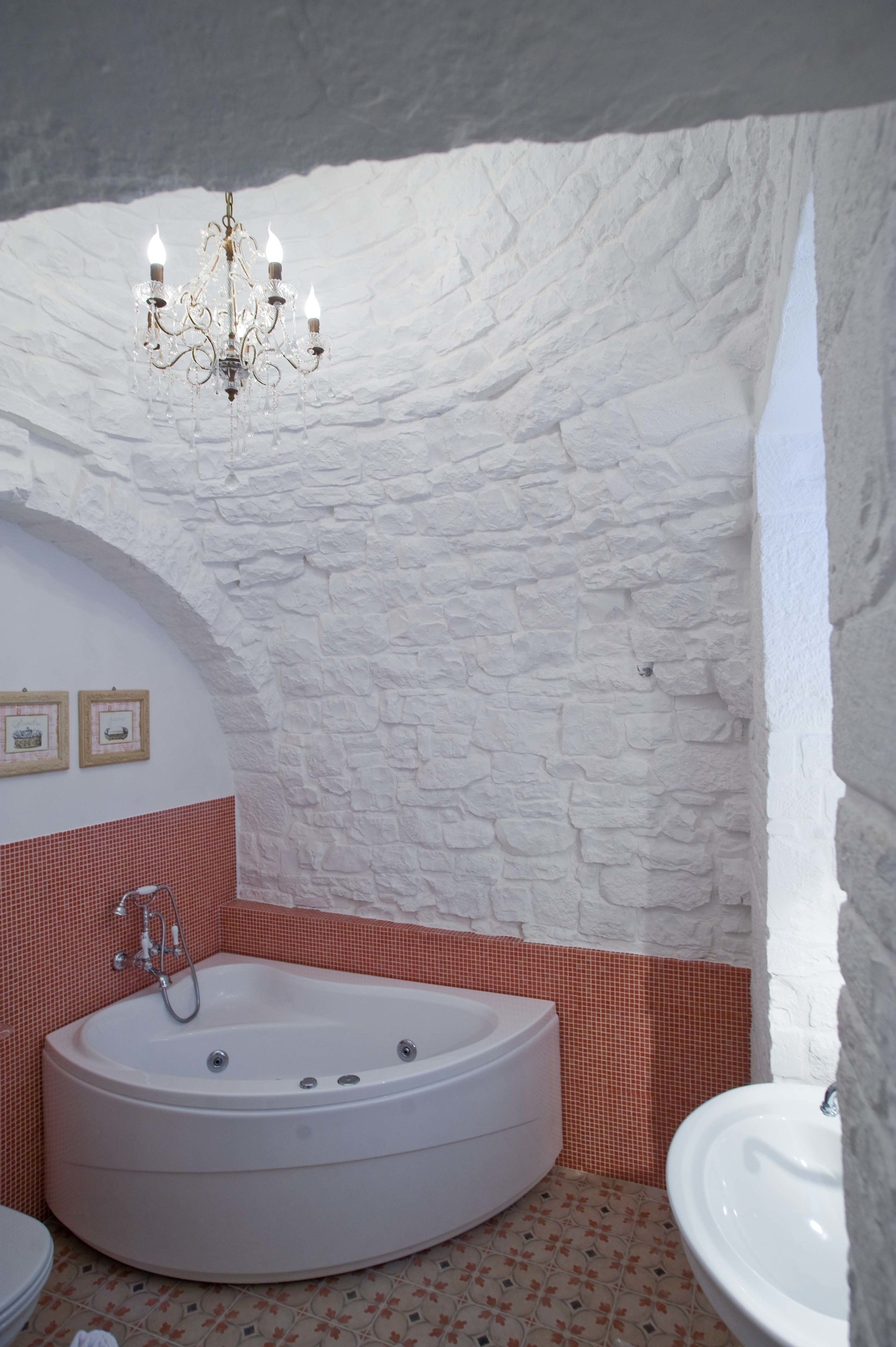 A bathroom with a white bathtub, a sink, and a chandelier.
