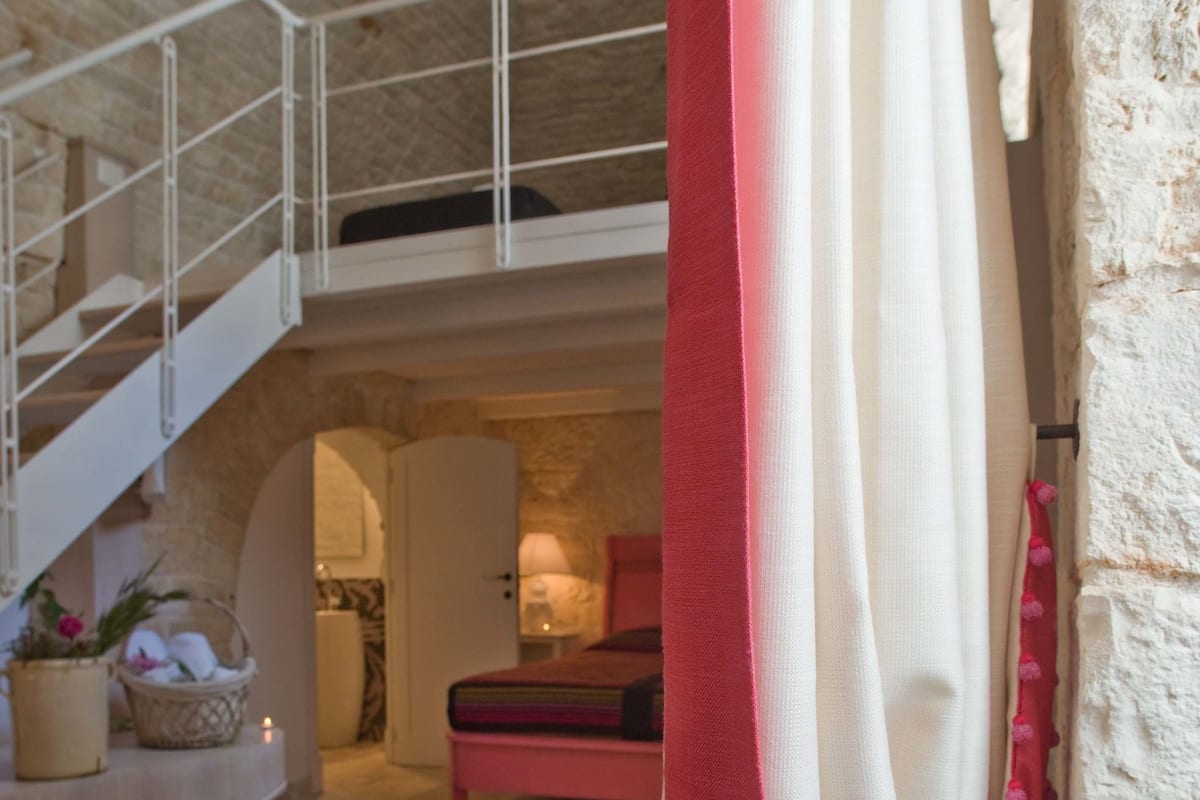 Un intérieur spacieux avec un escalier menant à un niveau supérieur, un banc et un panier rempli de fleurs.