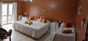 A hotel room with two beds, a small table, a chair, and a view of the outside.