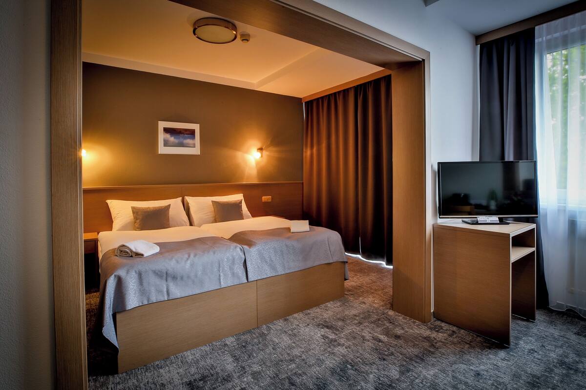 Une chambre d’hôtel avec un grand lit, un bureau doté d’un téléviseur à écran plat et une vue sur l’extérieur.