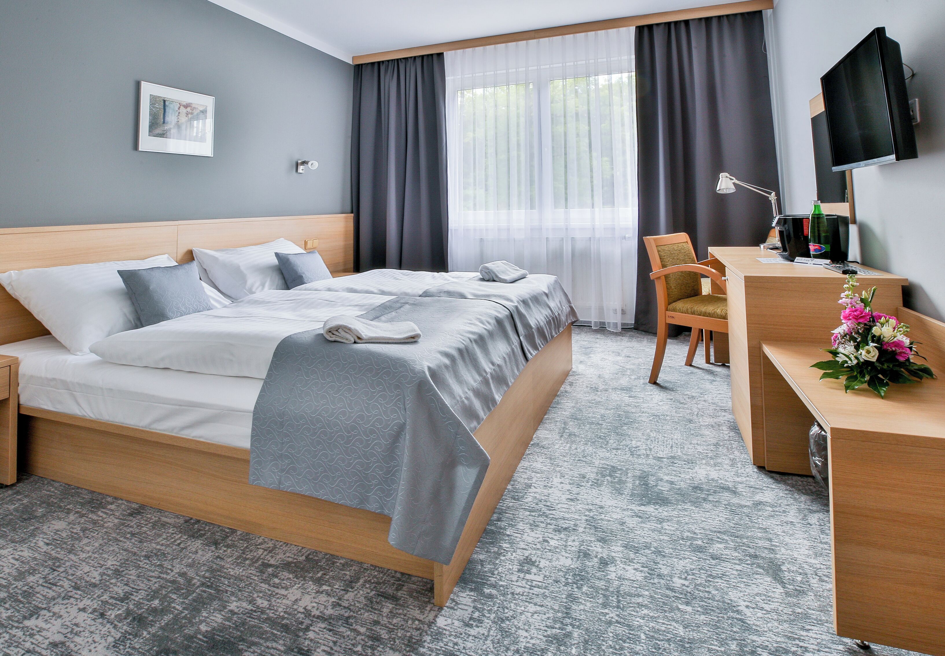 Una habitación de hotel con cama, escritorio, silla y televisor.