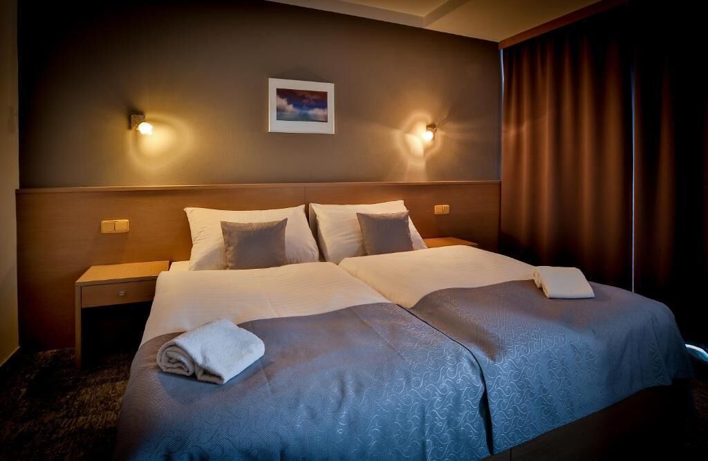 Un letto matrimoniale con due cuscini, un comodino e una lampada fissata alla parete.