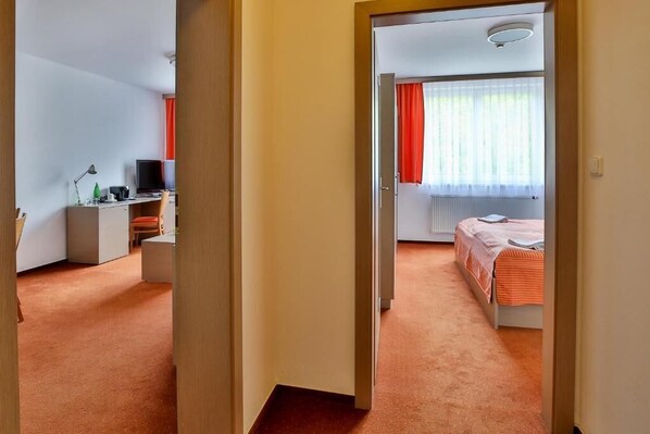 Una habitación de hotel con una cama, un escritorio, una silla, un televisor y una ventana con cortinas.