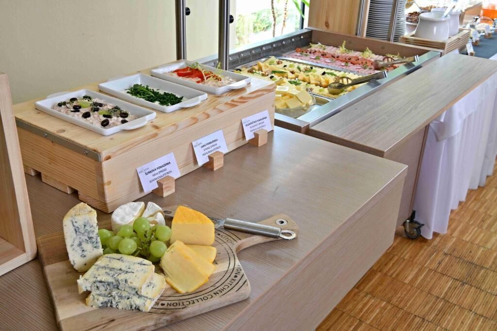 Un buffet con diverse opzioni gastronomiche, tra cui formaggi, frutta e insalate.