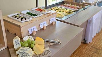 Un buffet con diverse opzioni gastronomiche, tra cui formaggi, frutta e insalate.
