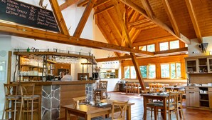 A rustic wooden interior with a bar area, stone accents, and large windows.