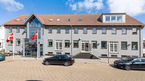 Un hôtel avec un toit recouvert de tuiles, de nombreuses fenêtres et une entrée bien visible.