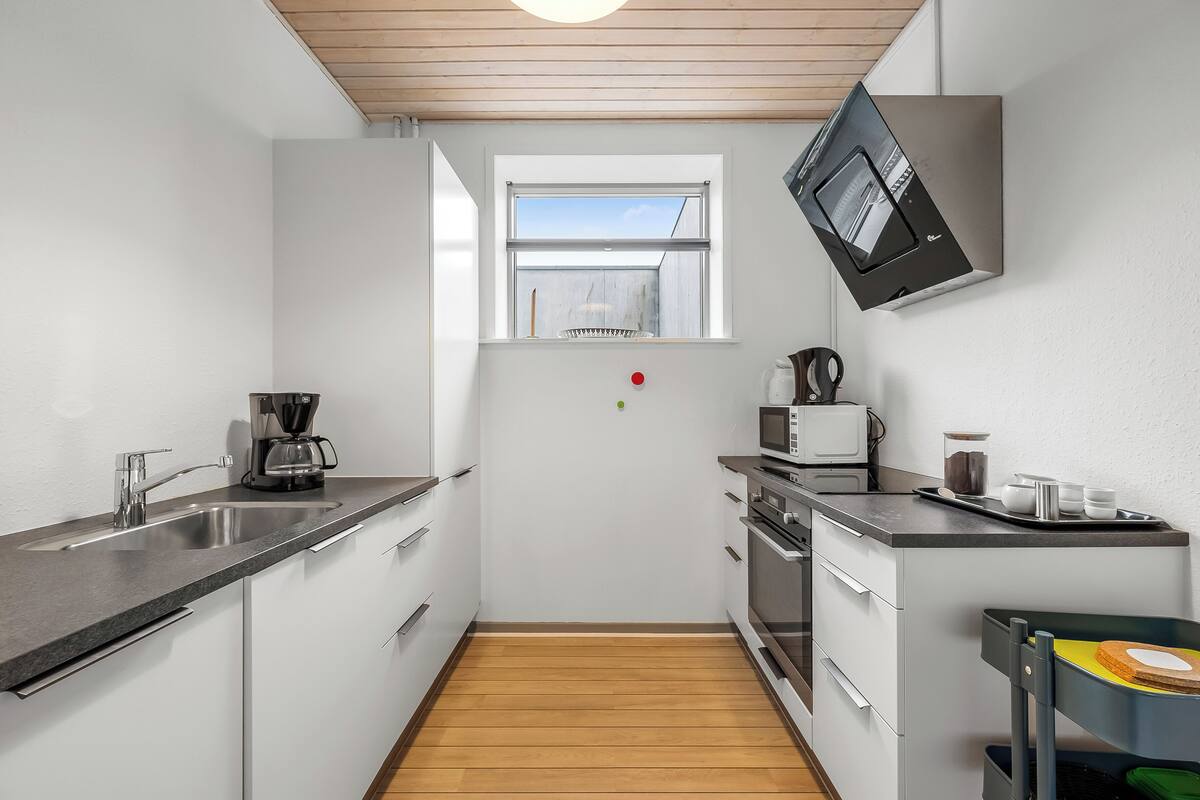 Una cocina moderna con horno empotrado, microondas y cafetera.
