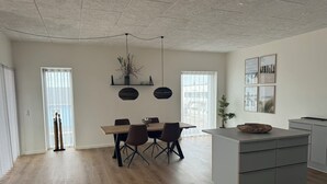 Un salon moderne comprenant un coin repas, un îlot de cuisine et une grande fenêtre laissant entrer la lumière naturelle.