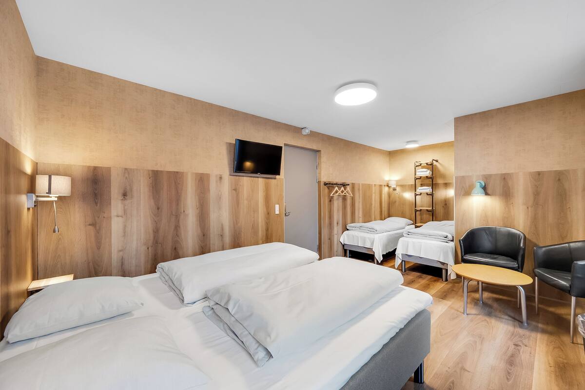 Habitación de hotel con dos camas, televisión, escritorio y una silla.