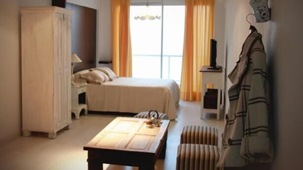 Une chambre à coucher avec un lit, une table en bois, une armoire et un porte-manteau.