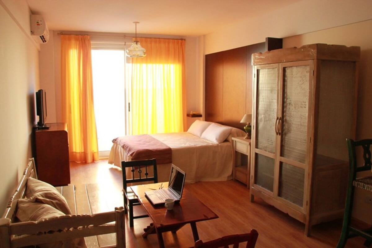 Ein Hotelzimmer mit einem Bett, einem Schreibtisch mit einem Laptop, einem Kleiderschrank und einem Fernseher.