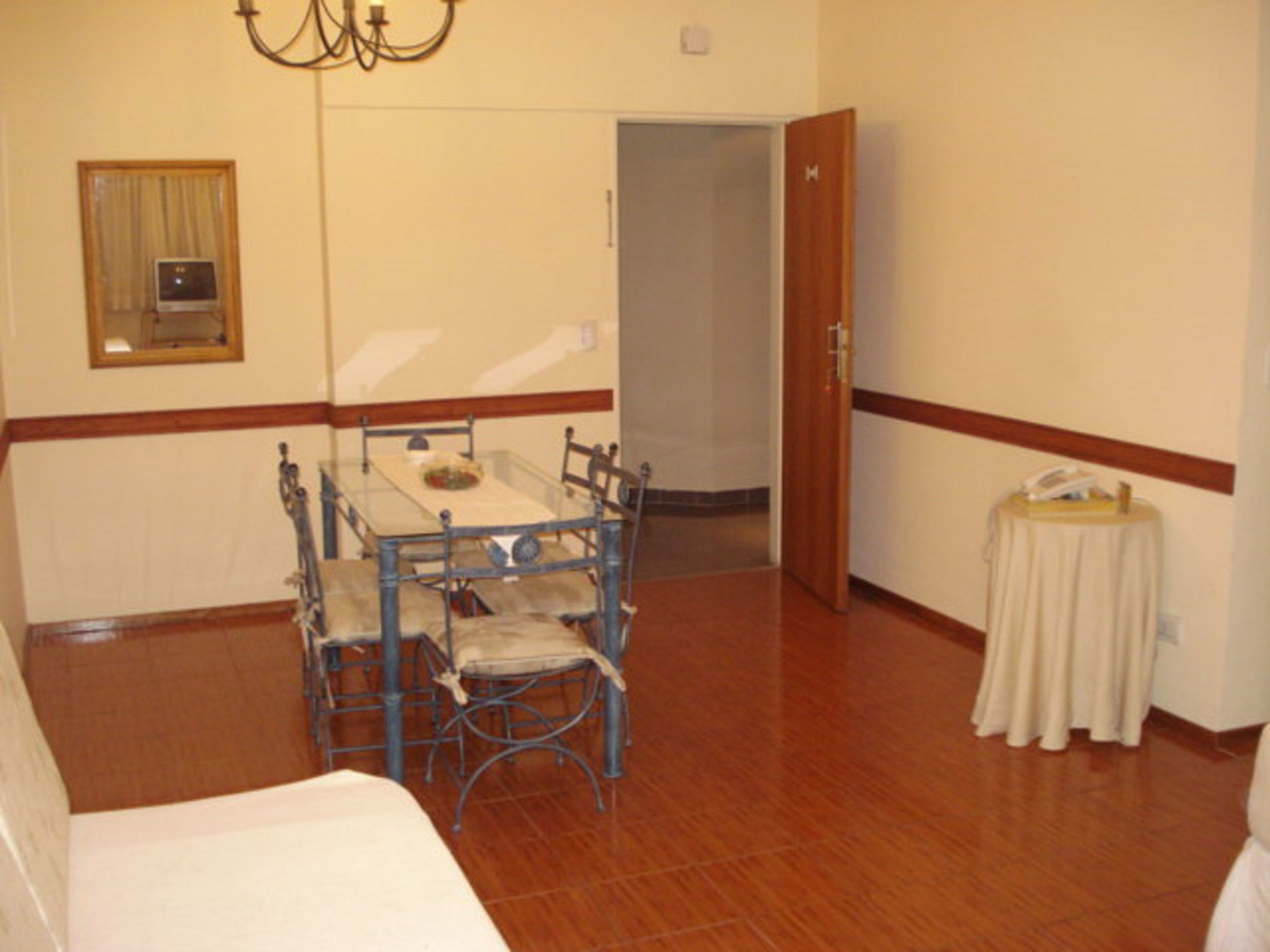 A dining area with a table and chairs, a chandelier, a door, and a small table with a telephone.