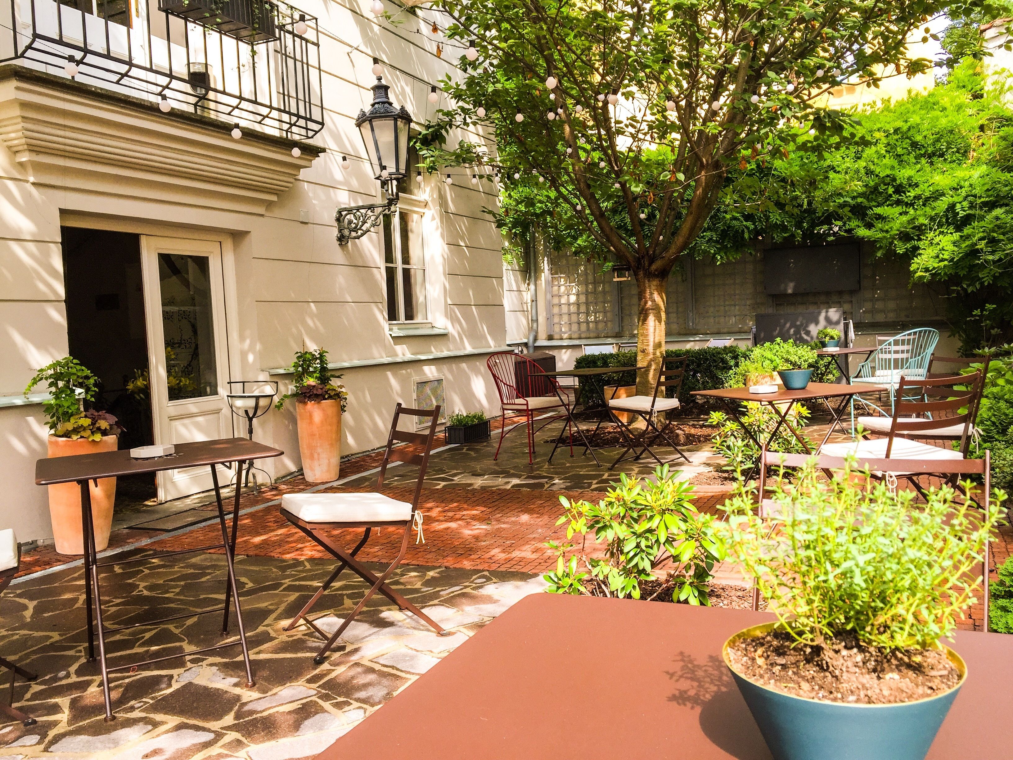 Une terrasse extérieure avec un sol en pierre, des sièges et des plantes en pot.