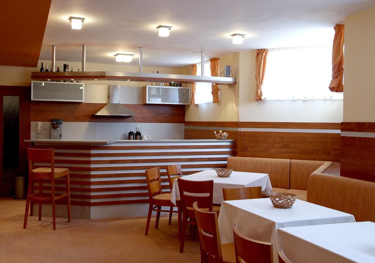 A restaurant with a bar area, wooden chairs, tables, and a sofa.