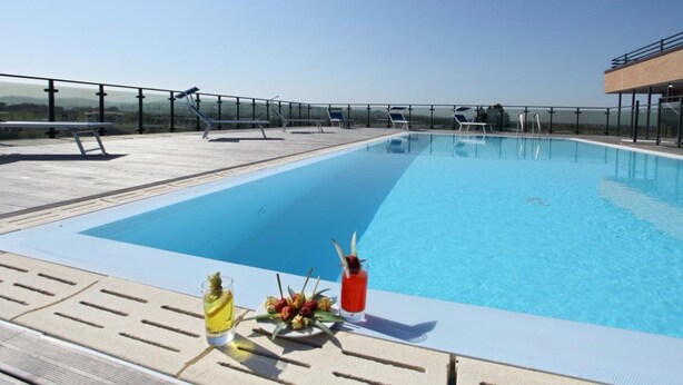 A rooftop pool with clear blue water, sun loungers, and a table with drinks and fruit. - Grand Hotel Forlì (Forlì)
