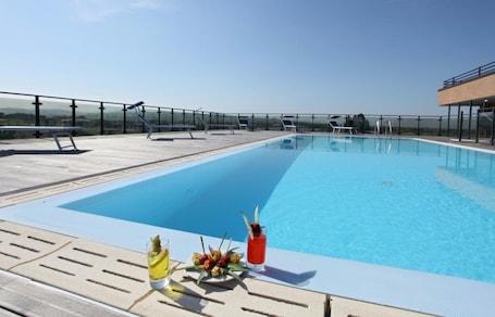 Una piscina al aire libre, sillones reclinables de piscina