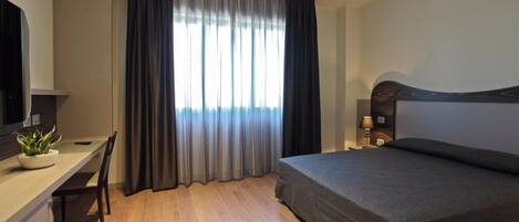 Una habitación de hotel moderna con cama, escritorio y televisión.