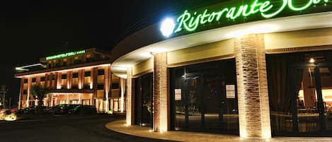 Un hôtel qui se distingue par une enseigne bien visible, « Ristorante 3 Corri », et qui présente un design moderne avec des colonnes en briques et de grandes portes vitrées.