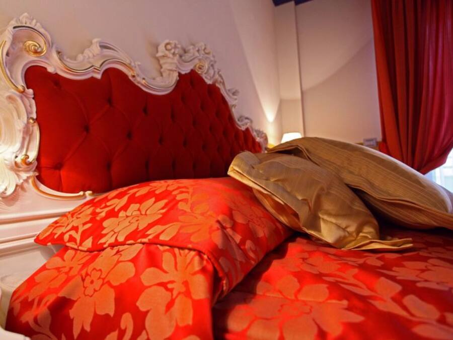 A bed with a red upholstered headboard and floral-patterned bedding.