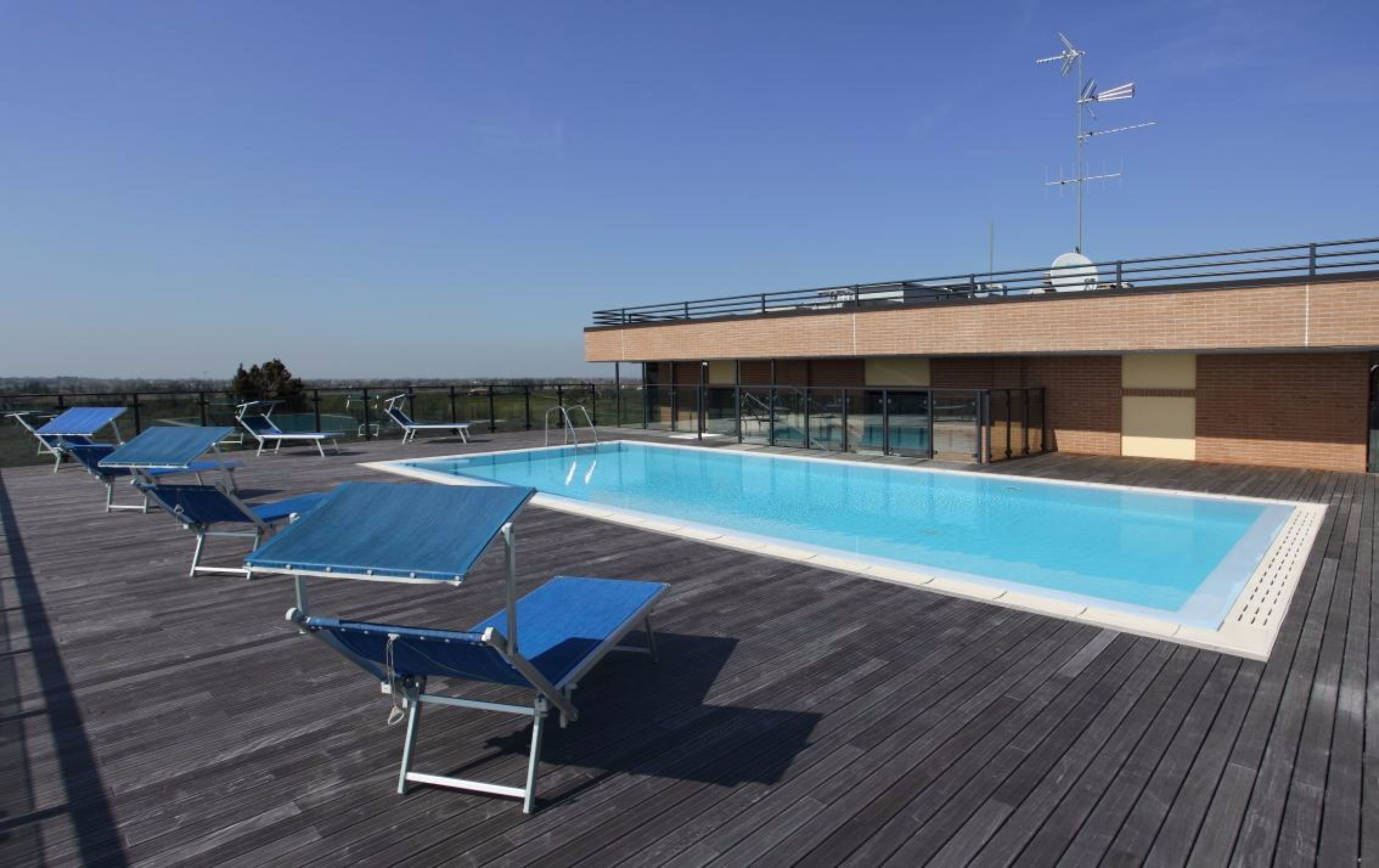 A rooftop pool area with blue sun loungers and a clear blue sky.