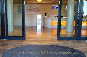 Un espace d’accueil d’hôtel comprenant un comptoir d’accueil, un écran numérique et un bureau de réception.