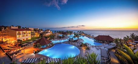 A resort with multiple swimming pools, lounge areas, and beachfront views.
