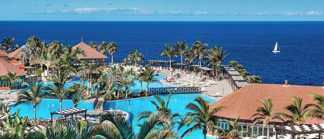 A resort with a large pool, palm trees, and a view of the ocean.