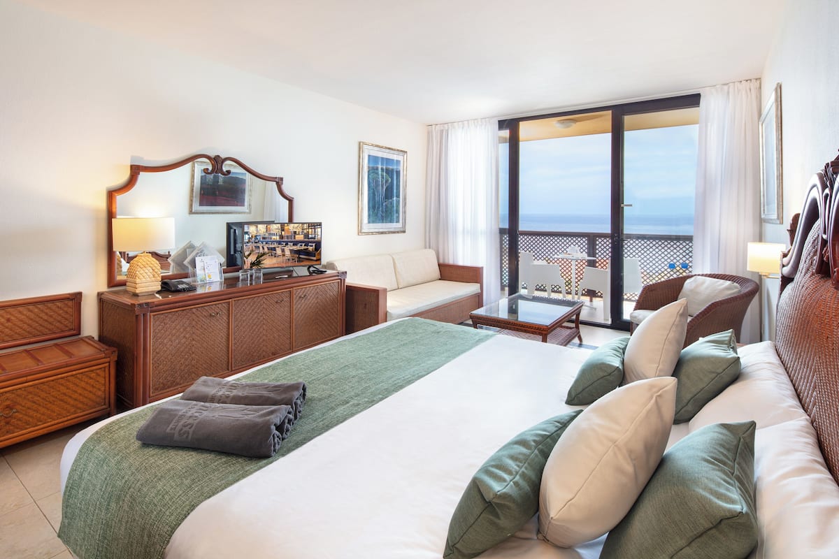 Une chambre d’hôtel avec un grand lit, un canapé, un bureau et un balcon avec vue.
