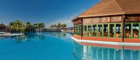 A large, clear swimming pool with a wooden structure on one side.