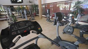 Une salle de sport équipée de machines de cardio, de machines de musculation et d’un écran de télévision.