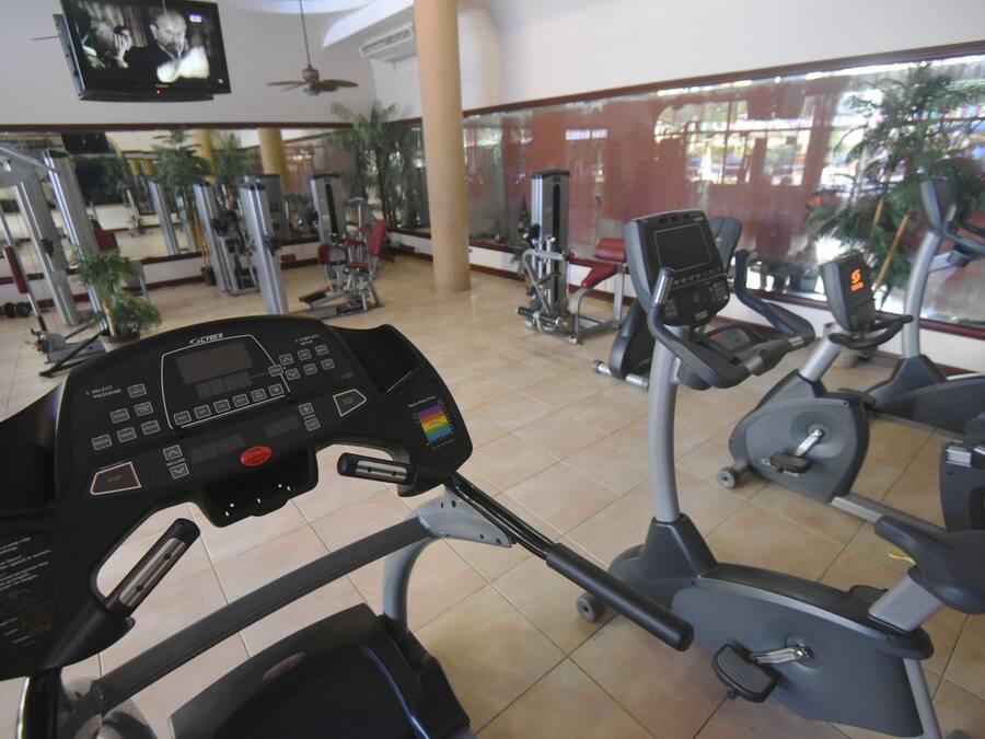 Une salle de sport équipée de machines de cardio, de machines de musculation et d’un écran de télévision.