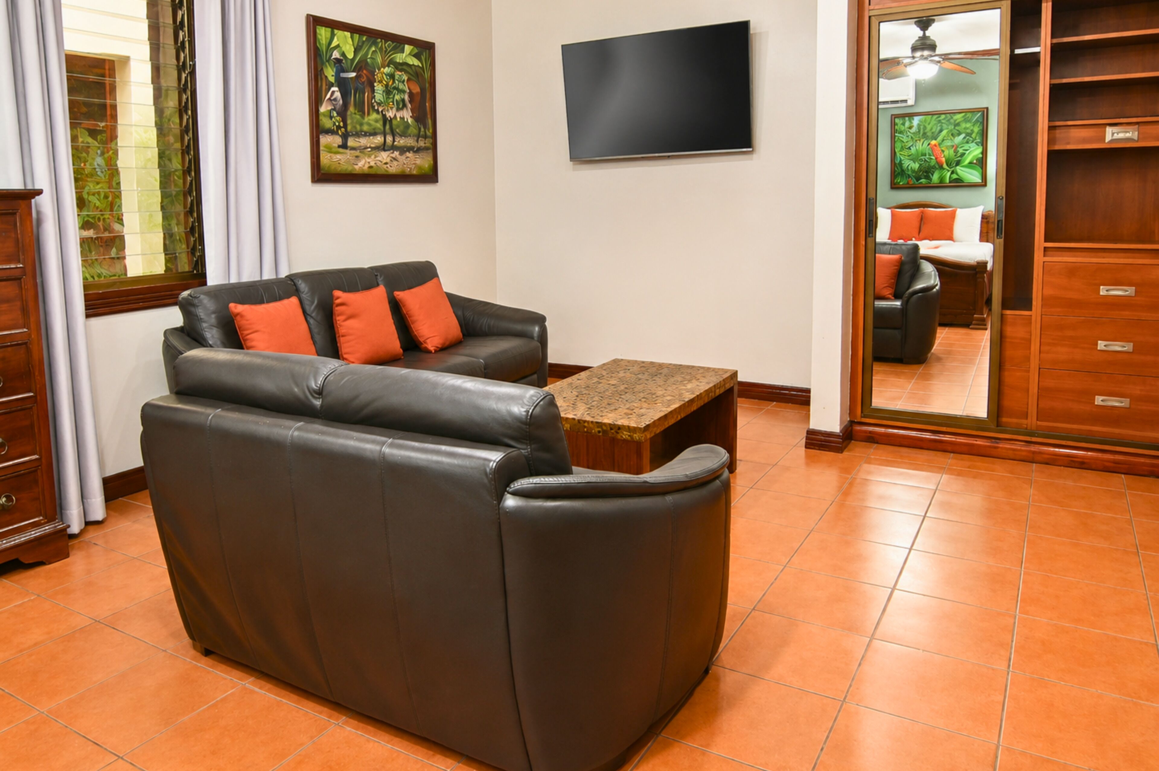 Una sala de estar con un sofá de cuero, un televisor y un mueble de madera.