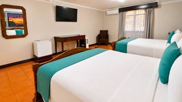 Habitación de hotel con dos camas, un escritorio, una silla, un televisor y una ventana con cortinas.