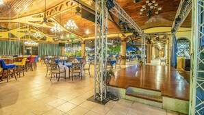 A spacious restaurant with high ceilings, wooden beams, and a central bar area.