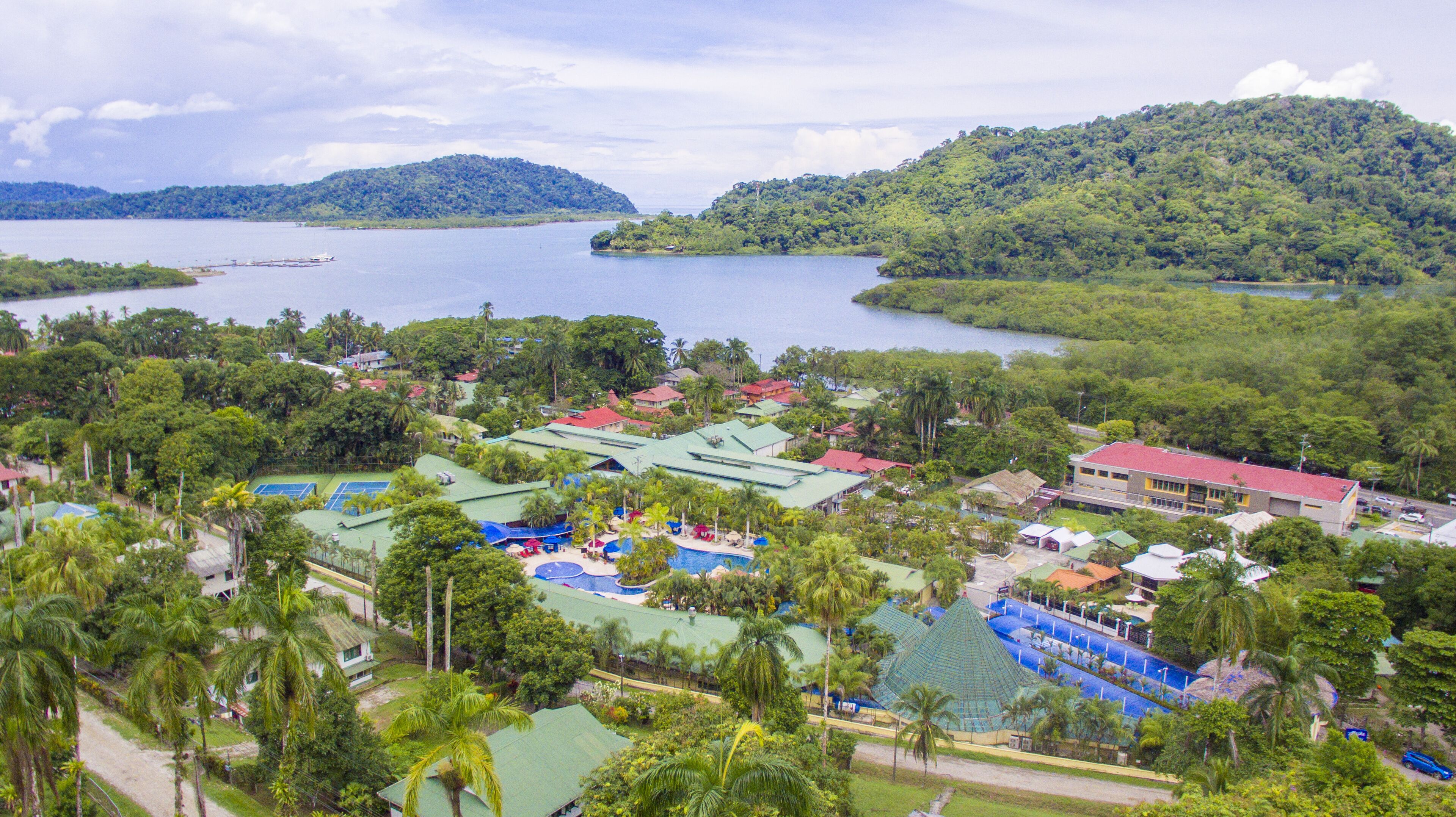 Ein Resort mit mehreren Gebäuden, einem Pool und üppiger Vegetation rund um einen See.
