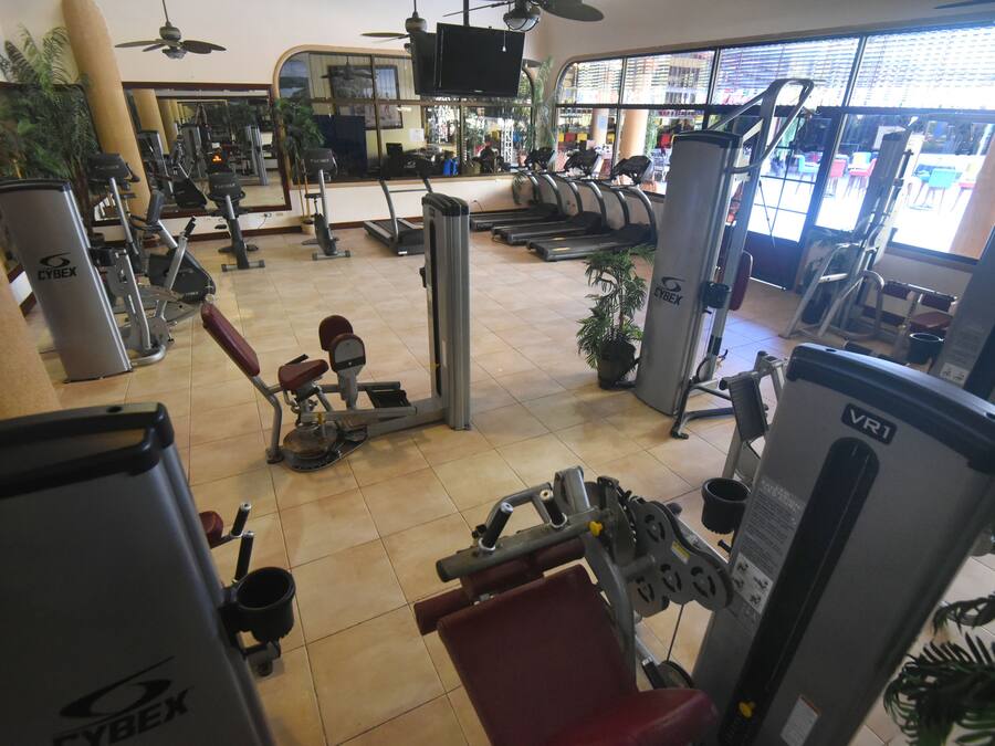 A gym with various exercise equipment, including treadmills, weight machines, and a stationary bike.