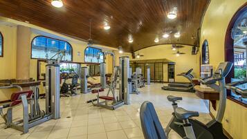 Un gimnasio con diversos equipos de ejercicio, amplias ventanas y techo de madera.
