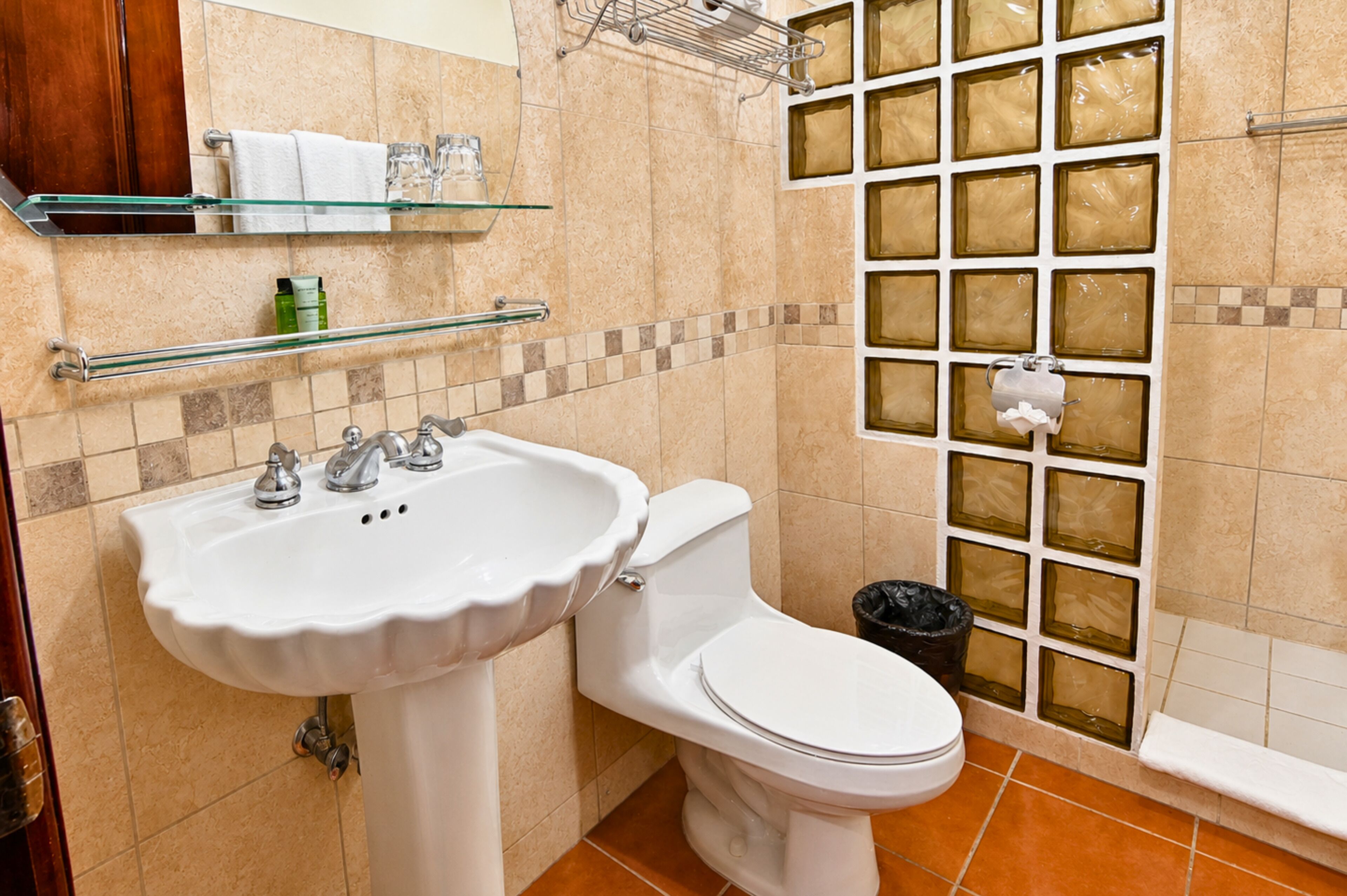 A bathroom with a white sink, toilet, and a glass shower enclosure.