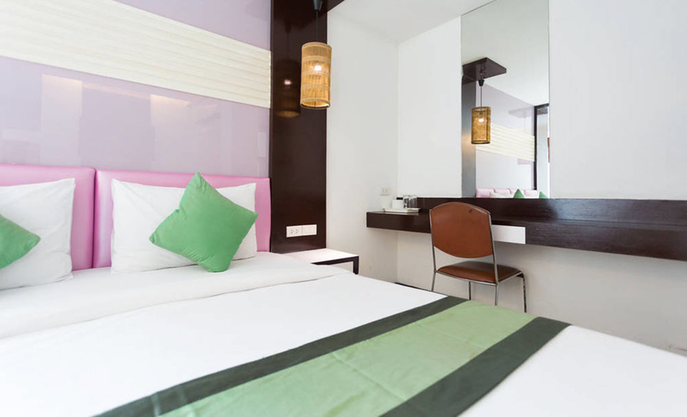 Una camera d'albergo con un letto, una scrivania, una sedia e un grande specchio.