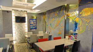 Un salón de conferencias con una gran mesa, sillas, un televisor y coloridas obras de arte en las paredes.