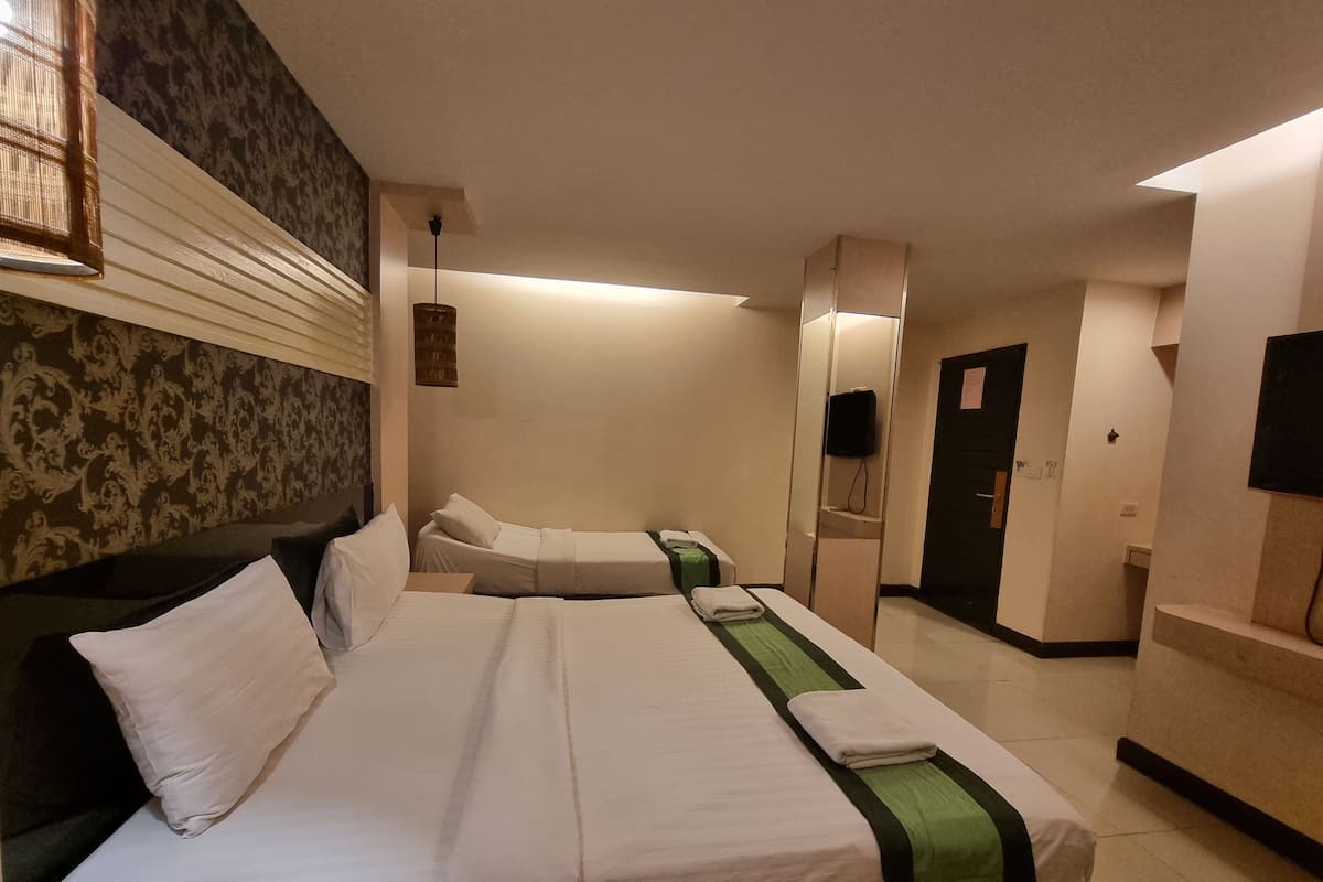 A hotel room with a large bed, a bedside table, a mirror, and a television.