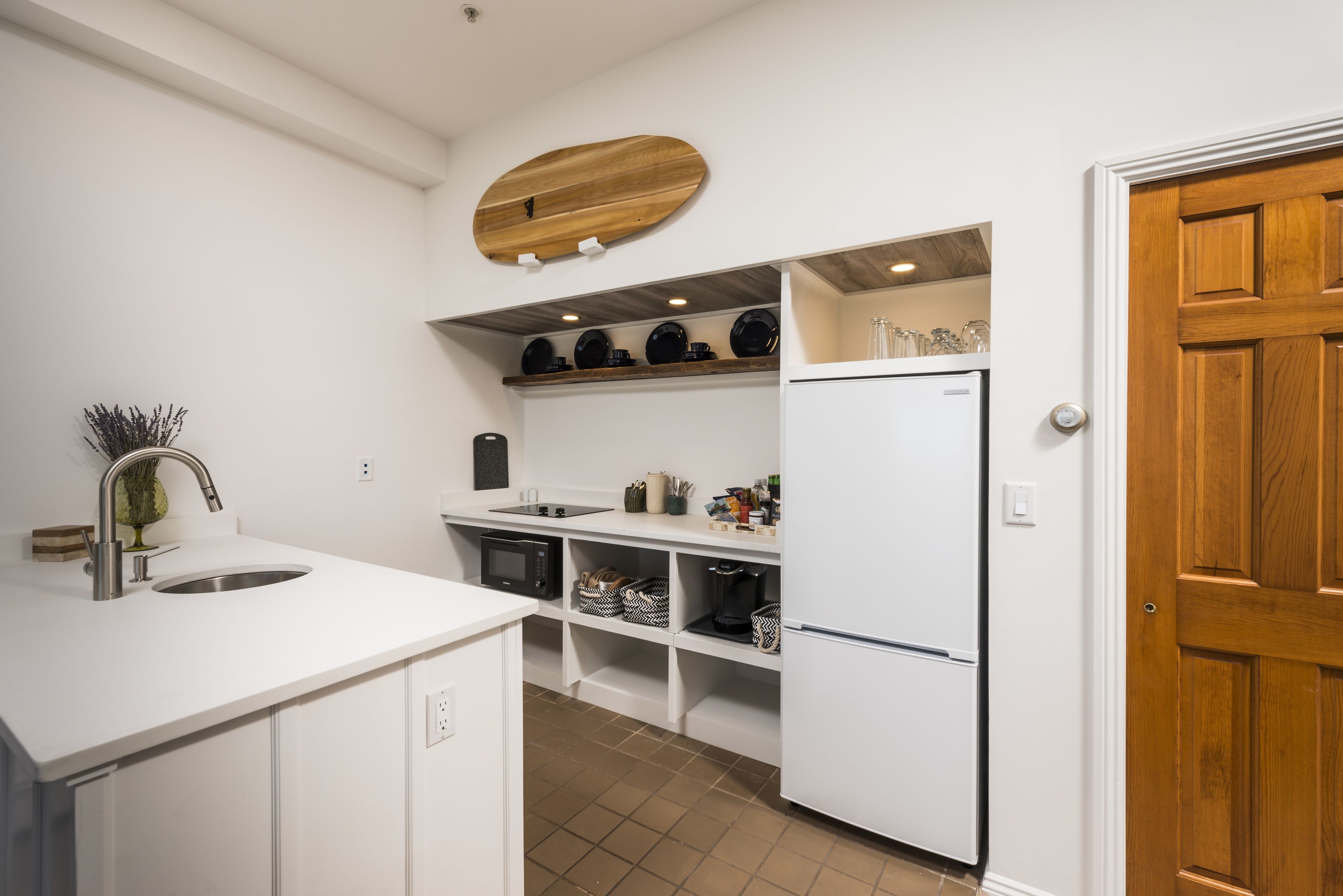 A modern kitchen with white cabinetry, a built-in oven, and a refrigerator.