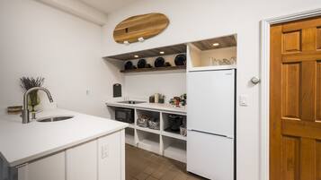 A modern kitchen with white cabinetry, a built-in oven, and a refrigerator.